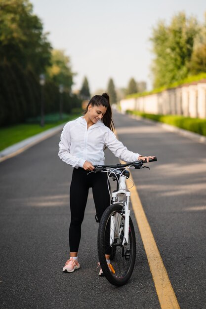 Schönes Mädchen, das am weißen Fahrrad aufwirft