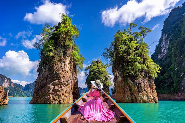 Schönes Mädchen, das auf dem Boot sitzt und Berge in Ratchaprapha Dam am Khao Sok Nationalpark, Surat Thani Provinz, Thailand sucht.