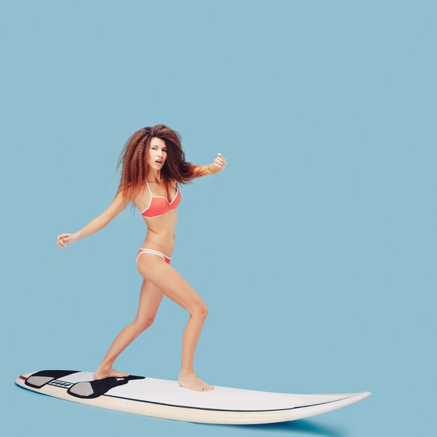 Schönes Mädchen, das auf Surfbrett steht