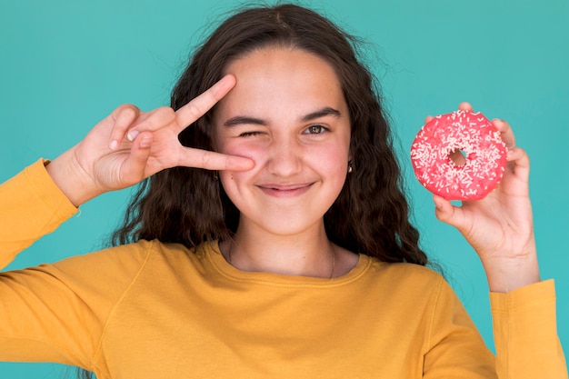 Kostenloses Foto schönes mädchen, das einen glasierten krapfen anhält