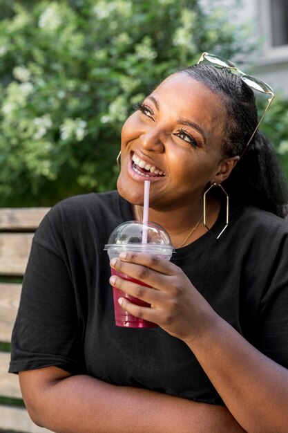 Schönes Mädchen, das einen Smoothie draußen trinkt