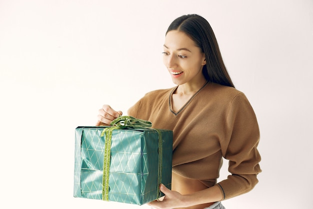 Schönes Mädchen, das in einem Studio mit Geschenken steht