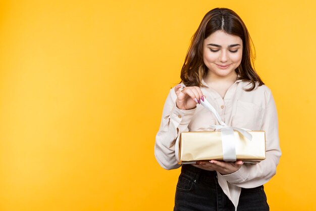 Schönes Mädchen, das versucht, ihr Geschenk zu öffnen Foto in hoher Qualität