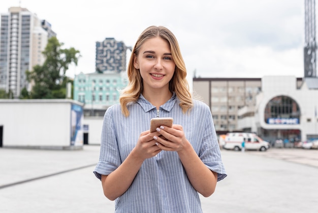 Kostenloses Foto schönes mädchen der vorderansicht, das ein telefon anhält