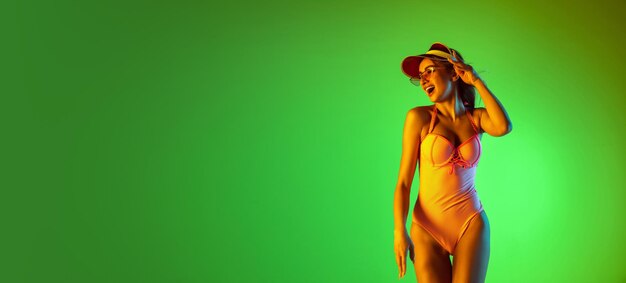 Schönes Mädchen im modischen Badeanzug isoliert auf Farbverlaufsstudio im Neonlicht