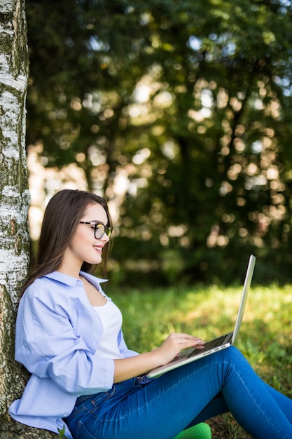 Schönes Mädchen in Blue Jeans arbeiten mit Laptop im Stadtpark