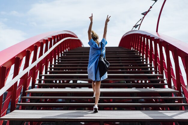 schönes Mädchen in einem blauen Kleid posiert auf der Brücke