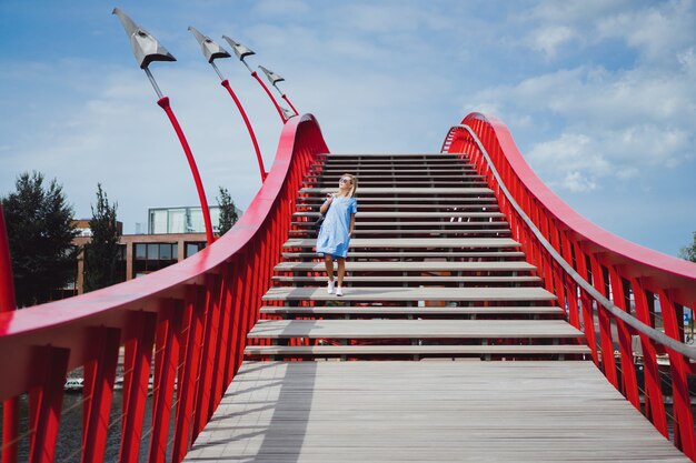 schönes Mädchen in einem blauen Kleid posiert auf der Brücke