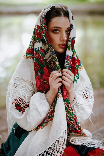 Schönes Mädchen in einem traditionellen ethnischen Kleid mit einem gestickten Umhang auf ihrem Kopf