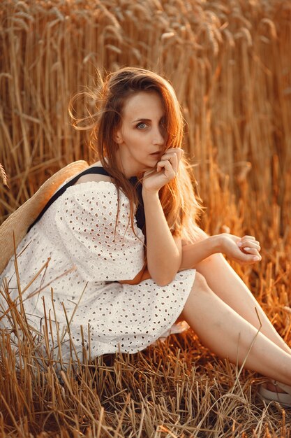 Schönes Mädchen in einem weißen Kleid. Frau in einem Herbstfeld. Dame in einem Strohhut.