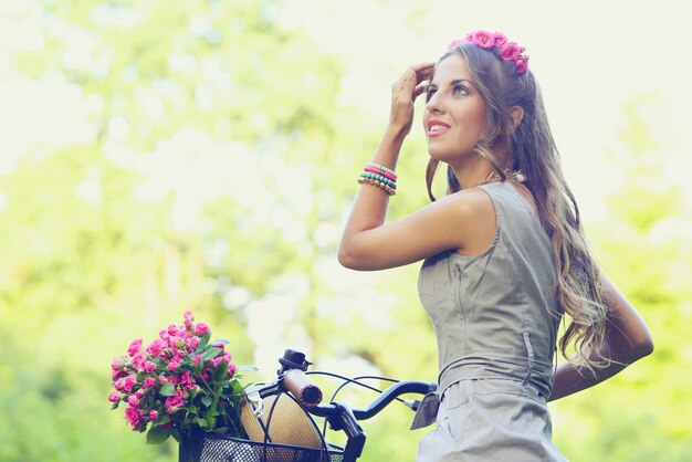 Schönes Mädchen mit Blumen auf einem Fahrrad