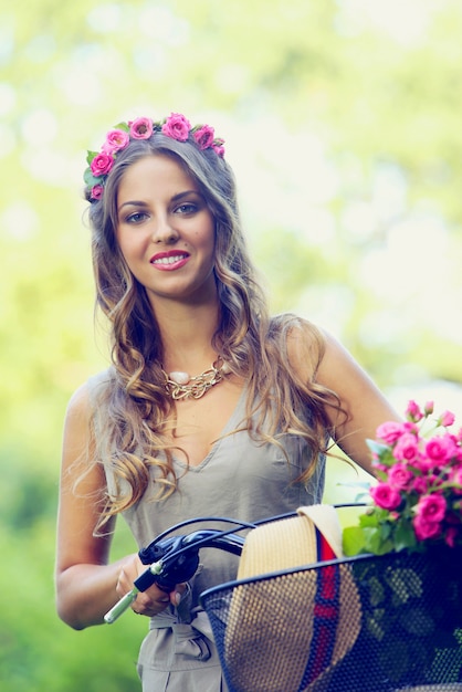 Schönes Mädchen mit Blumen auf einem Fahrrad