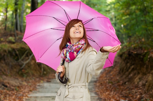 Schönes Mädchen mit Regenschirm, der für Regen prüft