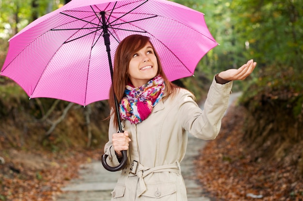 Schönes Mädchen mit Regenschirm, der für Regen prüft