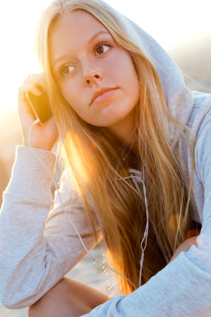 Schönes Mädchen sitzt auf dem Dach und hört Musik.