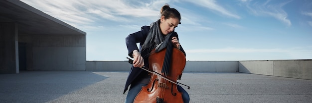 schönes Mädchen spielt das Cello mit Leidenschaft in einer konkreten Umgebung