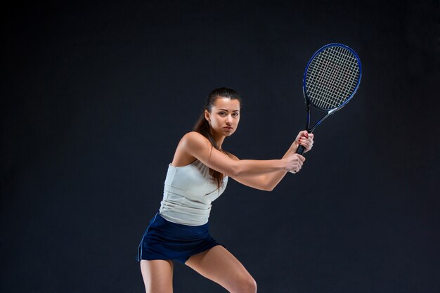 schönes Mädchen Tennisspieler mit einem Schläger auf dunklem Hintergrund