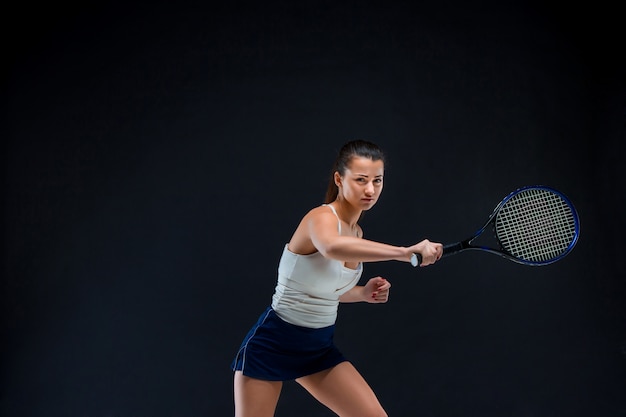 schönes Mädchen Tennisspieler mit einem Schläger auf dunklem Hintergrund