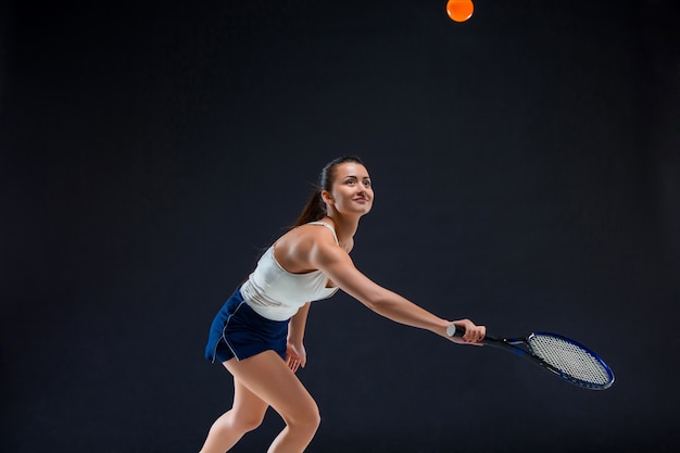 schönes Mädchen Tennisspieler mit einem Schläger auf dunklem Hintergrund