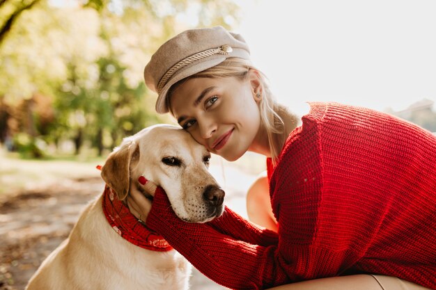 Schönes Mädchen und ihr Hund zusammen mit Liebe. Charmante blonde Frau mit ihrem Haustier, das sonnigen Herbsttag genießt.