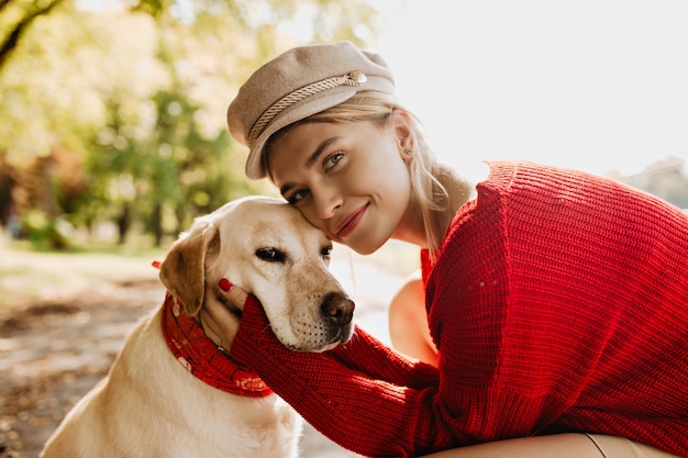 Schönes Mädchen und ihr Hund zusammen mit Liebe. Charmante blonde Frau mit ihrem Haustier, das sonnigen Herbsttag genießt.