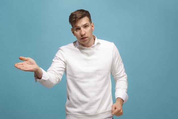 Schönes männliches halblanges Porträt lokalisiert auf blauem Studiohintergrund. Der junge emotional überraschte Mann