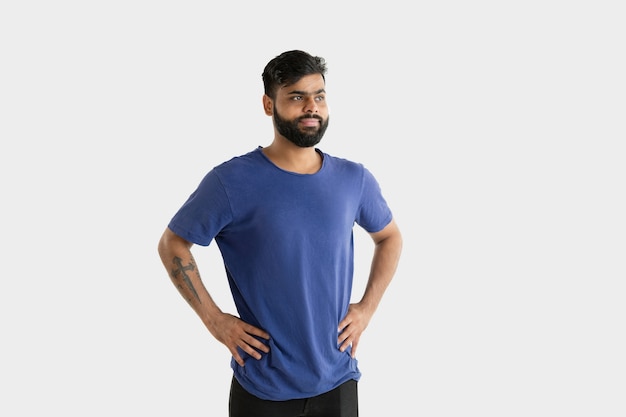 Schönes männliches Porträt lokalisiert. Junger emotionaler hinduistischer Mann im blauen Hemd. Gesichtsausdruck, menschliche Emotionen. Stehend und lächelnd.