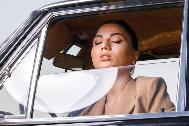 Schönes Model schloss die Augen und stand auf dem Fenster des Autos und atmete tief ein Foto in hoher Qualität