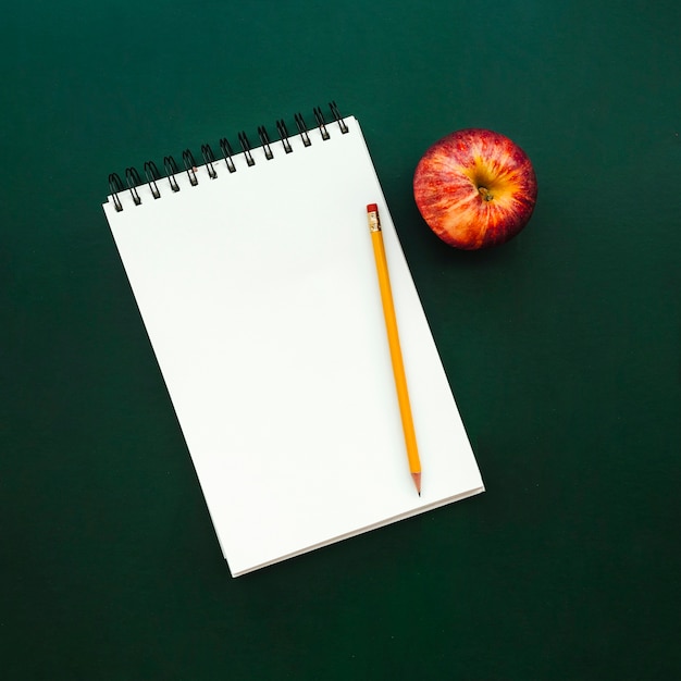 schönes Notizbuch mit Apfel und Bleistift auf Schultafel