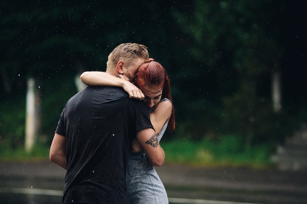 Schönes Paar, das sich draußen im Regen umarmt