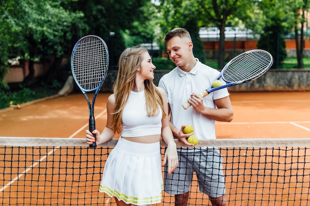 Schönes Paar, das Tennis spielt und glücklich zueinander schaut.