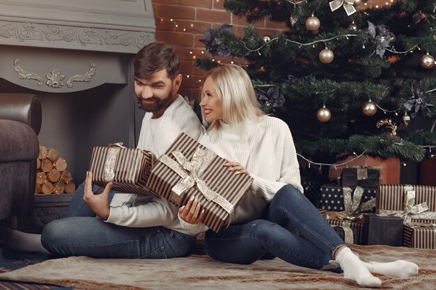 Schönes Paar, das zu Hause nahe Weihnachtsbaum sitzt