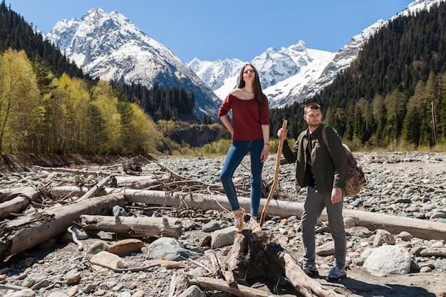 Schönes Paar des jungen Hipsters, das am Fluss im Wald wandert