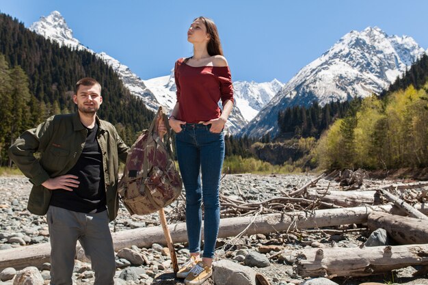 Schönes Paar des jungen Hipsters, das am Fluss im Wald wandert