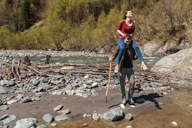 Schönes Paar des jungen Hipsters, das am Fluss im Wald wandert