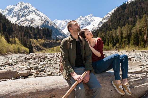 Schönes Paar des jungen Hipsters, das am Fluss im Wald wandert