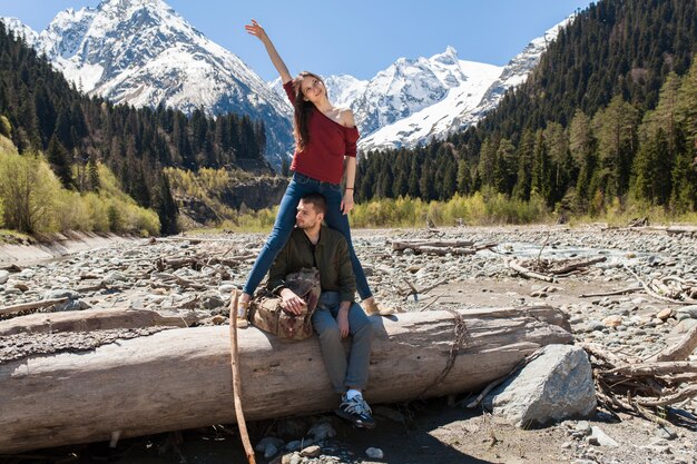 Schönes Paar des jungen Hipsters, das am Fluss im Wald wandert