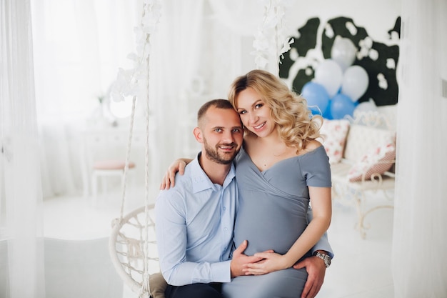 Schönes Paar gutaussehender Mann und schwangere Frau in langem grauem Kleid, das Smartphone hält und Selbstporträt macht