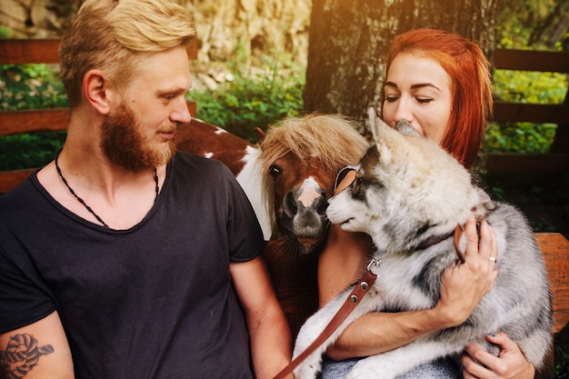 Schönes paar zusammen mit einem hund, der auf einer schaukel stillsteht. foto des paares aus nächster nähe. neben pony