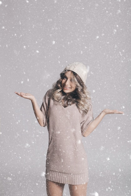 Schönes Porträt der jungen attraktiven Frau in gestrickter Kleidung auf schneebedecktem Hintergrund