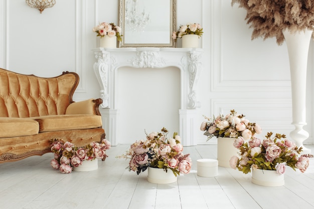 Schönes Provance-Wohnzimmer mit braunem Sofa nahe Kamin mit Blumen und Kerzen