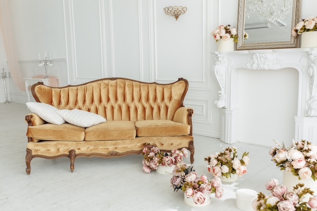 Schönes provenzalisches Wohnzimmer mit Weinlesebraun-Sofa nahe Kamin mit Blumen und Kerzen