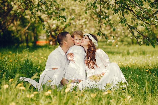 schönes schwangeres Mädchen in einem langen weißen Kleid mit ihrem Freund und ihrer kleinen Tochter