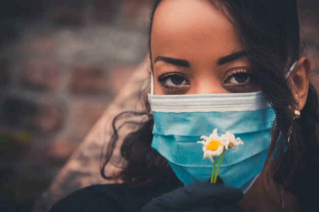 Schönes schwarzes Mädchen im Freien mit einer medizinischen Maske