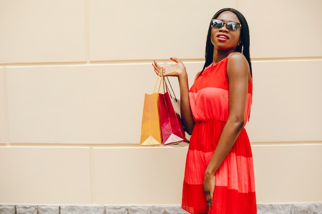Schönes schwarzes Mädchen mit Einkaufstüten in einer Stadt
