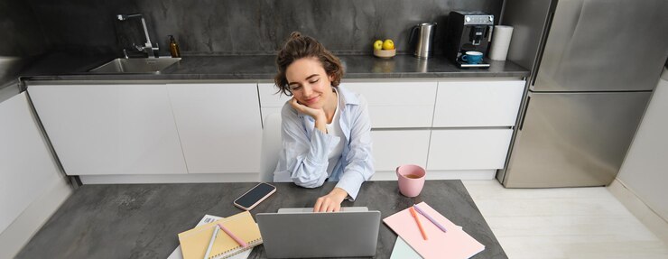 Kostenlose Foto schönes selbständiges mädchen arbeitet von zu hause aus, junge frau studiert online und schaut sich den kurs auf der website an
