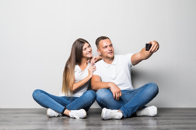 Schönes stilvolles Paar, das Selfie zusammen lokalisiert auf weißem Hintergrund macht