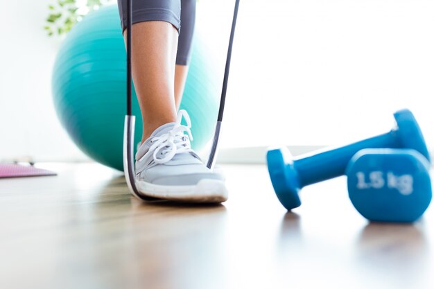 Schönes Training der jungen Frau mit Bändern zu Hause.