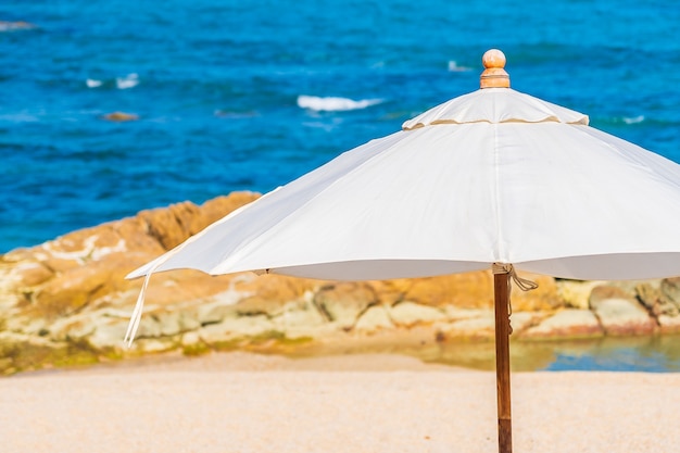 Kostenloses Foto schönes tropisches strandmeer mit regenschirm und stuhl um weiße wolke und blauen himmel für urlaubsreisen