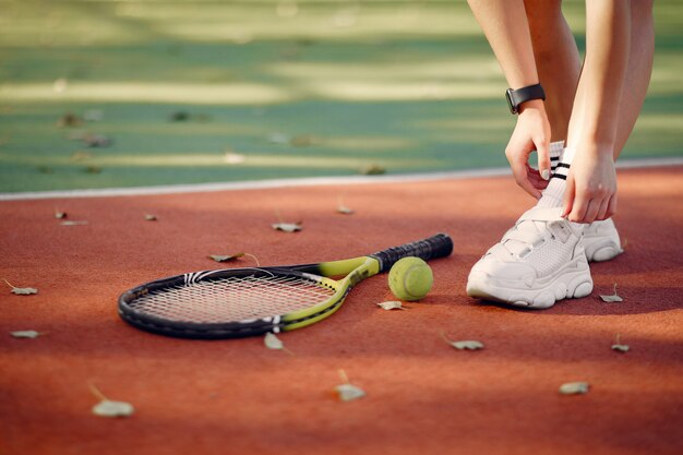 Schönes und stilvolles Mädchen auf dem Tennisplatz